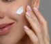 Mujer madura tocando suavemente su rostro con una expresión natural que refleja el cuidado preventivo de la piel y el envejecimiento facial.